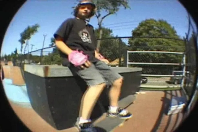 Skateboarder sitting on a ramp in a skate park.