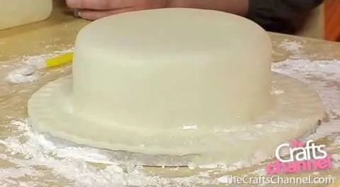 Cake covered in white fondant on a work surface.