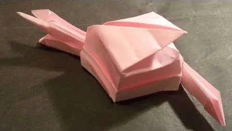 Pink origami turtle on a dark surface.