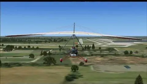 Aerial view of a hang glider flying over a green landscape.