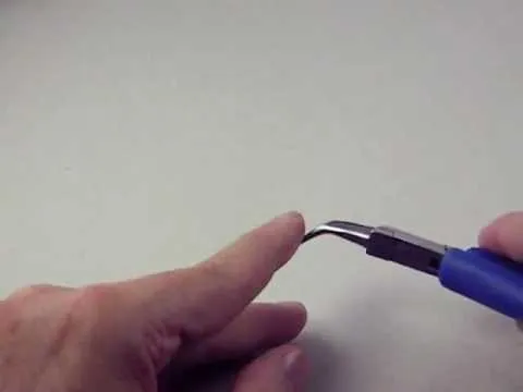Hand holding a precision tool with a curved tip.