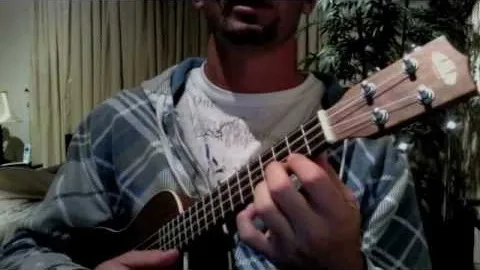 Person playing a ukulele indoors.