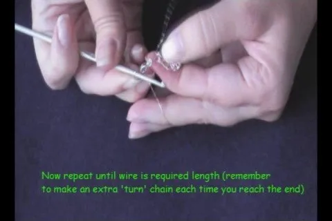 A person demonstrating wire crafting techniques with a focus on chaining.