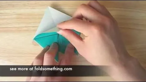 Hands folding a piece of paper into a geometric shape.