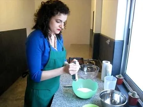 Woman mixing ingredients in a green bowl in a kitchen setting.