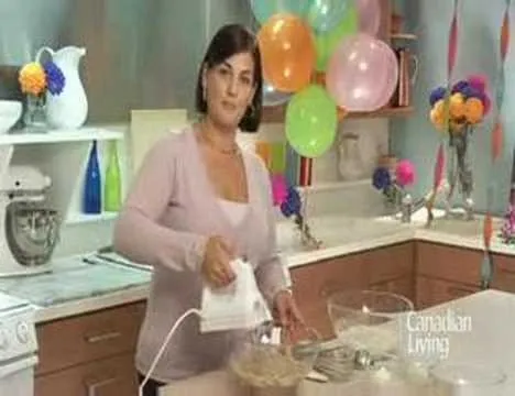 Woman using a hand mixer in a brightly decorated kitchen.