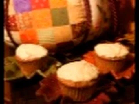 Three decorated cupcakes placed on a table with a colorful quilt in the background.