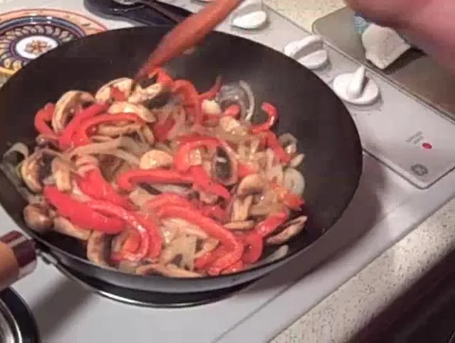 Stir-frying colorful bell peppers, onions, and mushrooms in a skillet.