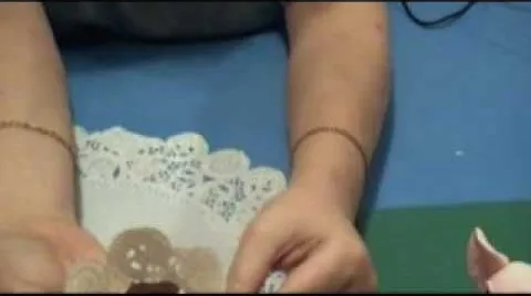 Person crafting or decorating a treat on a lace doily.