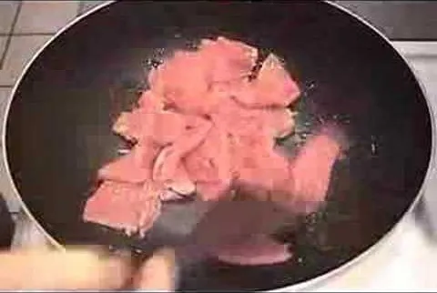 Sliced meat cooking in a frying pan.