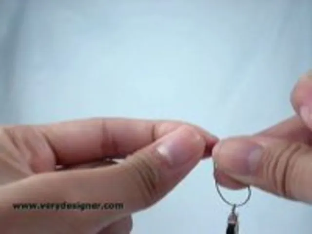 Hands demonstrating how to loop a small ring with a wire.