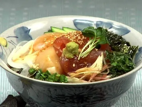 Fresh sashimi bowl garnished with vegetables and sesame seeds.