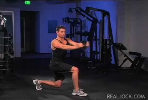 Man performing a lunge exercise in a gym setting.