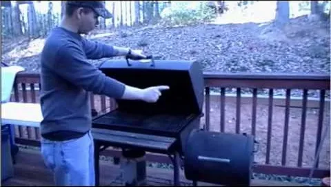 Man grilling outdoors, pointing at an open grill.