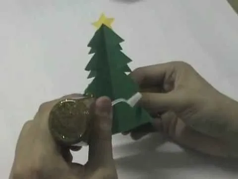 Origami Christmas tree being decorated with a gold ornament.