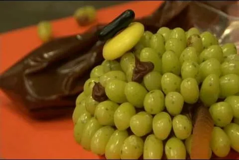 Creative fruit arrangement featuring green grapes resembling a character with chocolate accents.