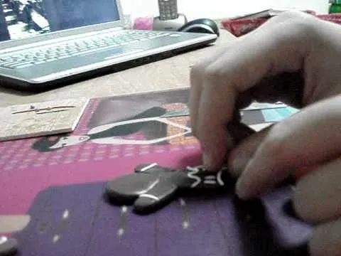 A person decorating a gingerbread cookie on a table.