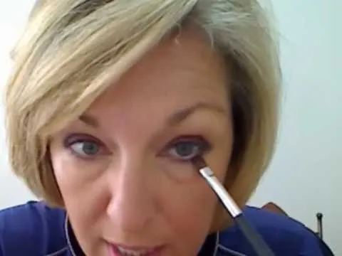 Woman applying makeup to her eyes using a brush.