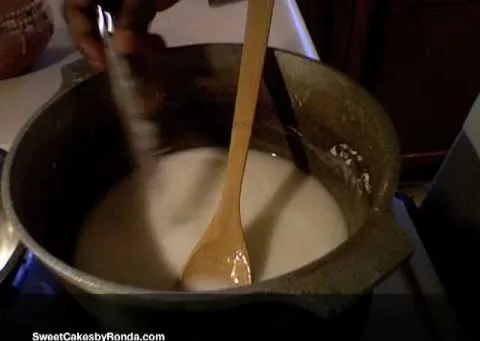 Stirring a creamy mixture in a pot with a wooden spoon.