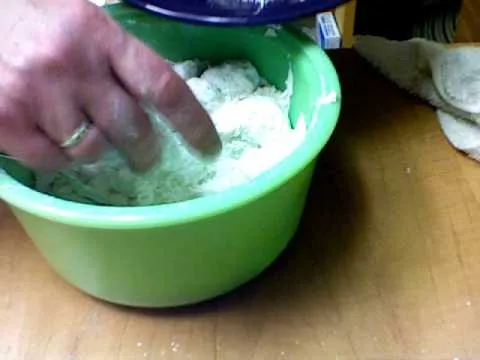 Hand mixing ingredients in a green bowl.