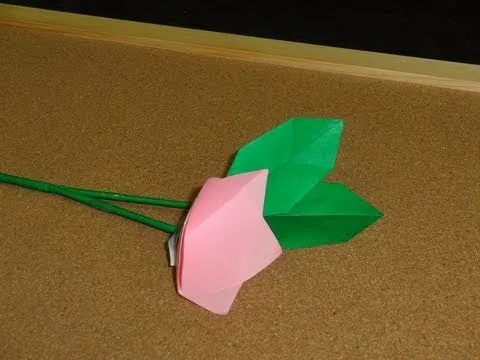 Folded origami flower with green leaves and pink petals.