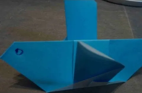 Blue origami boat on a surface.