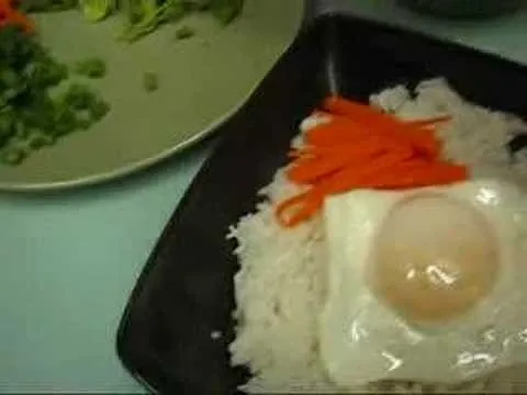 Fried egg on rice with sliced carrots.