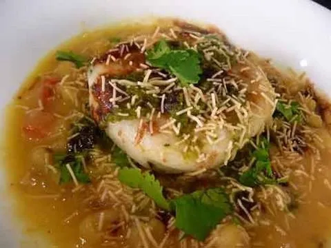 Delicious plate of savory Indian dish topped with herbs and grated cheese.