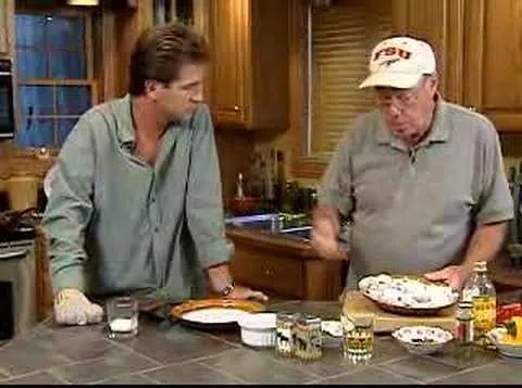 Cooking demonstration in a kitchen, featuring two chefs discussing a dish.
