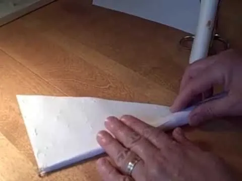 Older man demonstrating a craft project at a table.