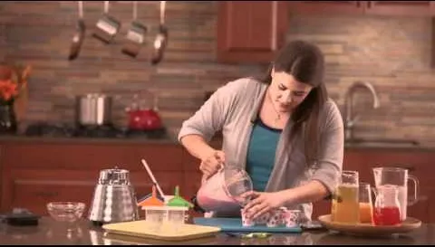 A woman preparing a smoothie in a modern kitchen.