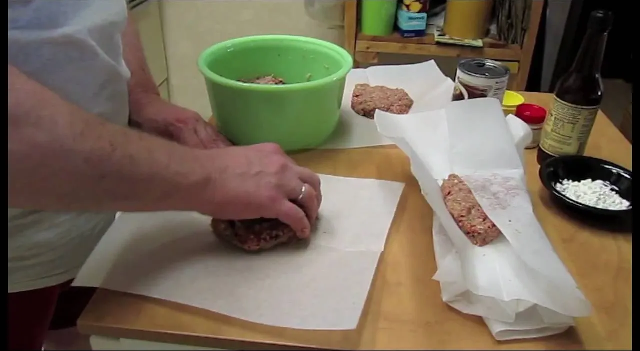 Person preparing hamburger patties in a kitchen setting.