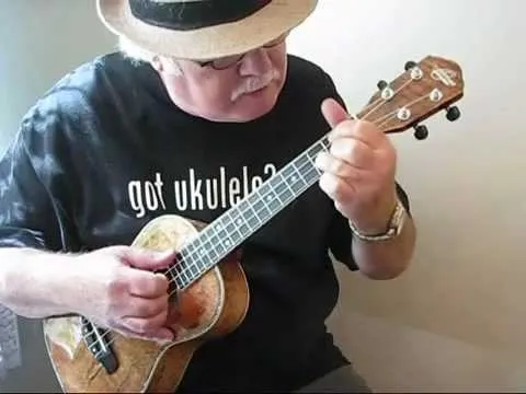 Man wearing a hat playing a ukulele.