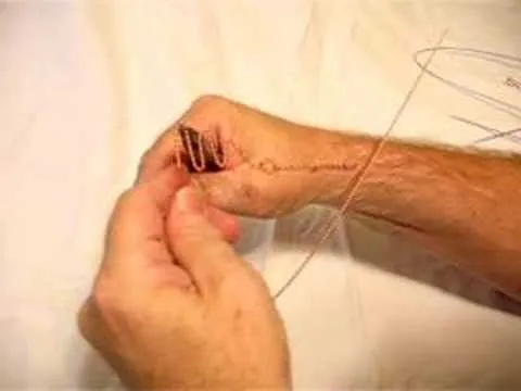 Hand threading a needle with a piece of thread.
