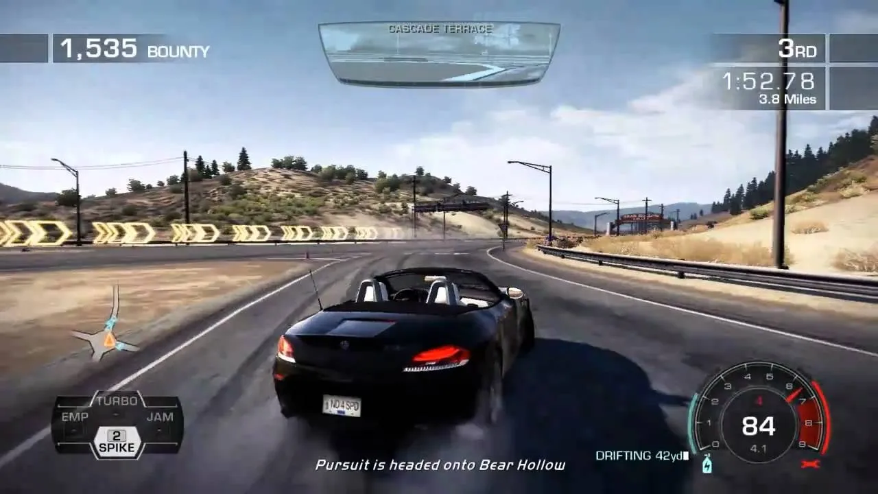 A black sports car racing on a winding road with a mountainous backdrop.