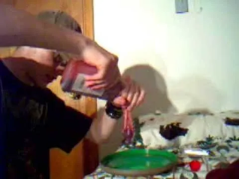 A person pouring a liquid onto a green plate in a kitchen setting.