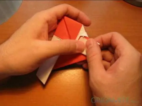 Hands folding red and white origami paper.