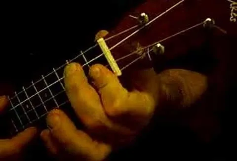 Close-up of hands playing a guitar, focusing on the fretboard and strings.