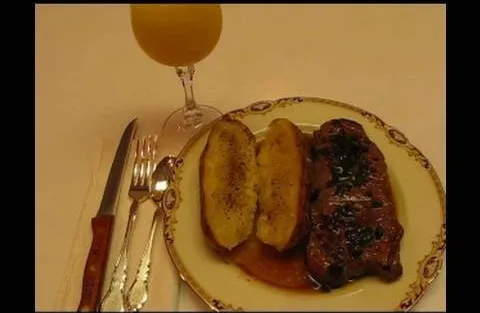 Grilled steak with roasted plantains and a glass of juice.