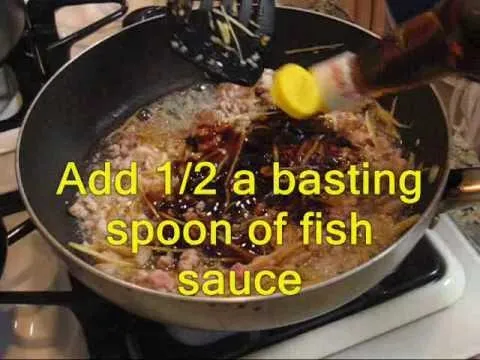 Adding fish sauce to a stir-fry in a skillet.