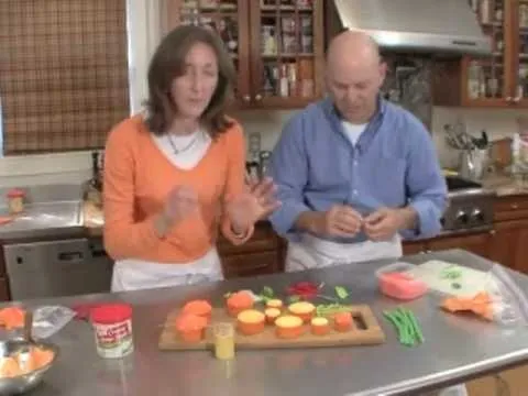 Cooking demonstration with two people preparing and garnishing vegetables on a kitchen countertop.