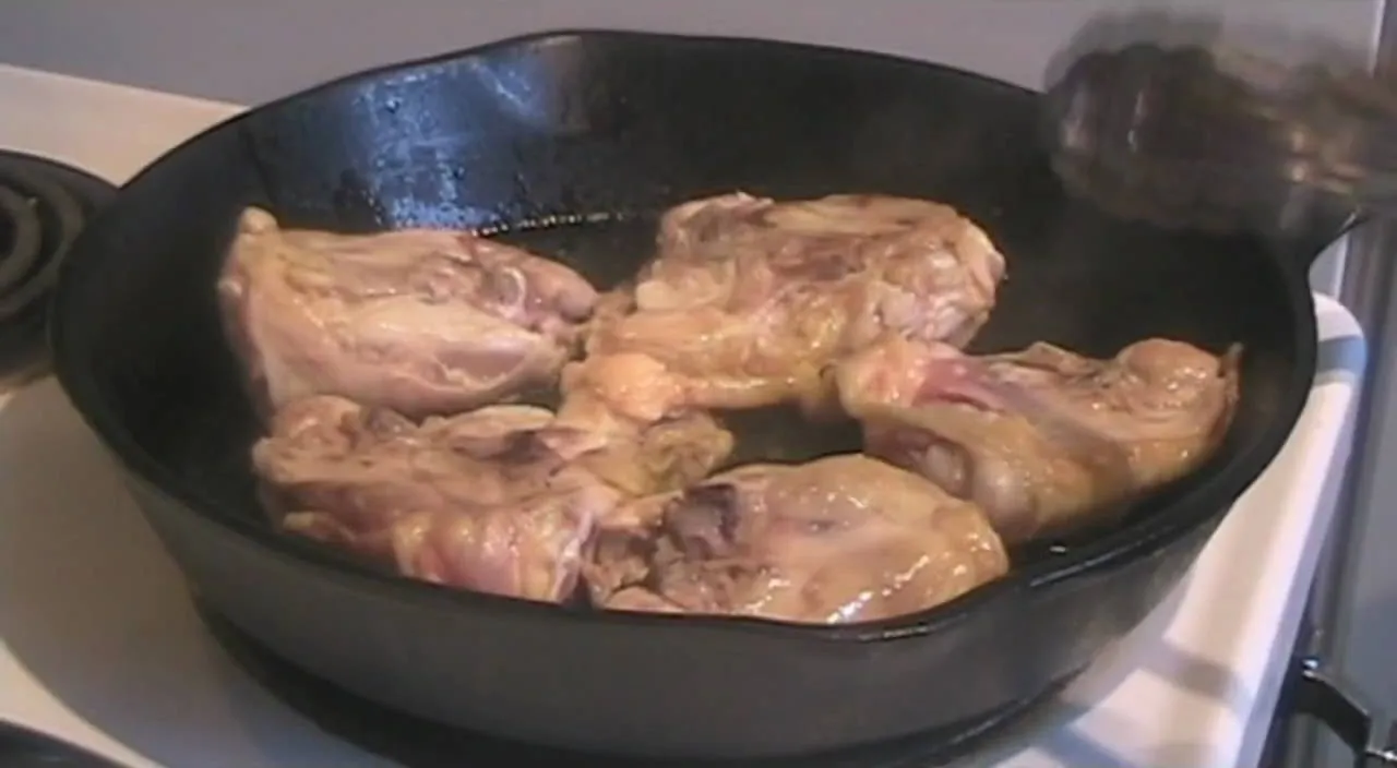 Cooking chicken thighs in a cast iron skillet.