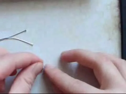 Hands manipulating a small pin on a table.