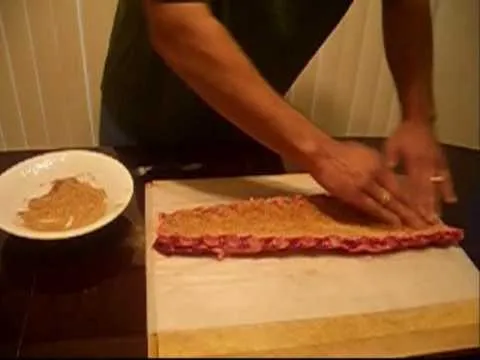 Barbecue ribs being seasoned on a wooden cutting board.