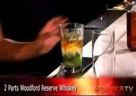 Whiskey cocktail being prepared at a bar.
