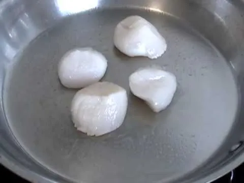 Seared scallops cooking in a pan.