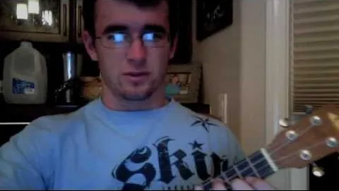 Person playing the ukulele indoors.