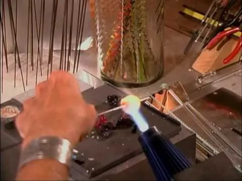 Glassblowing demonstration with a glass artist using a torch to shape molten glass.