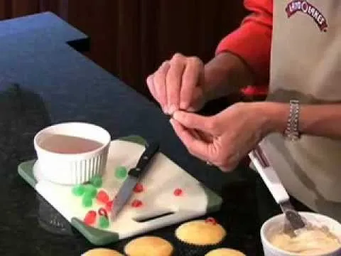 Baking hands assembling decorated cupcakes with colorful toppings.