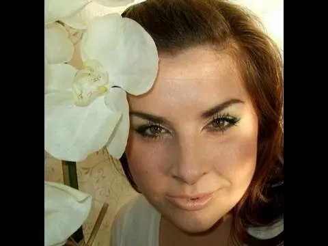 Woman with brown hair posing beside a white flower.